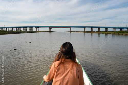 A woman on boat moving toward the bridge. © Vajirawich