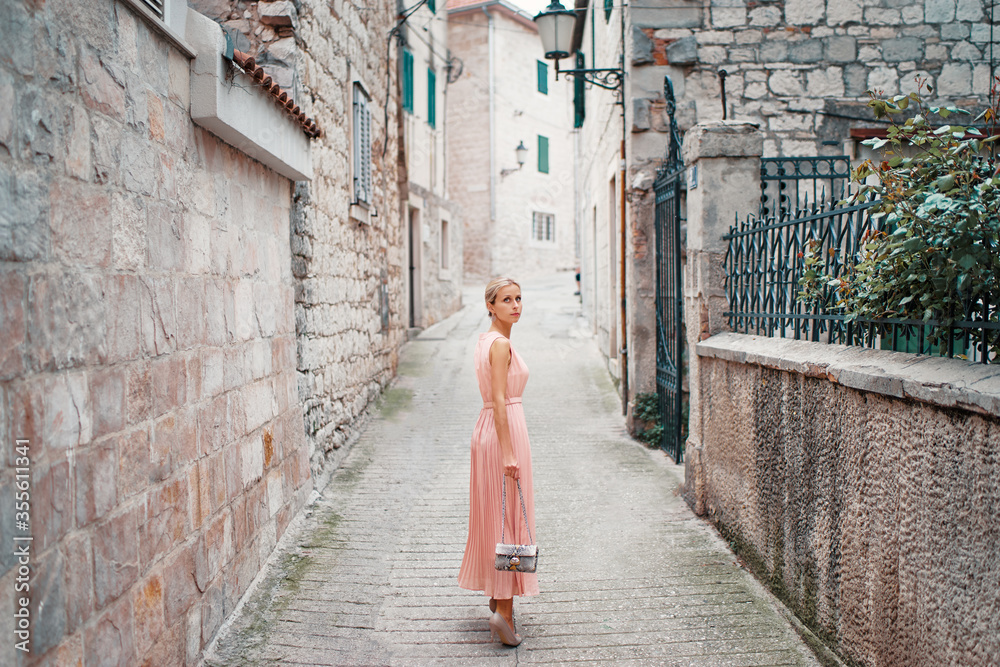 Traveling by Europe. Happy young woman in elegant dress walking by streets in Split, Croatia.