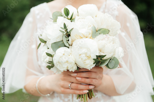 luxurious bouquet in the hands of the bride in a wedding dress and veil, rings 