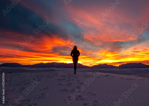 silhouette of a young woman in a cowboy hat reflecting on the sunset in White Sands National Park