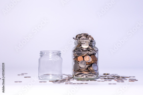Fototapeta Naklejka Na Ścianę i Meble -  Saving money by hand puting coins in jug glass on white background