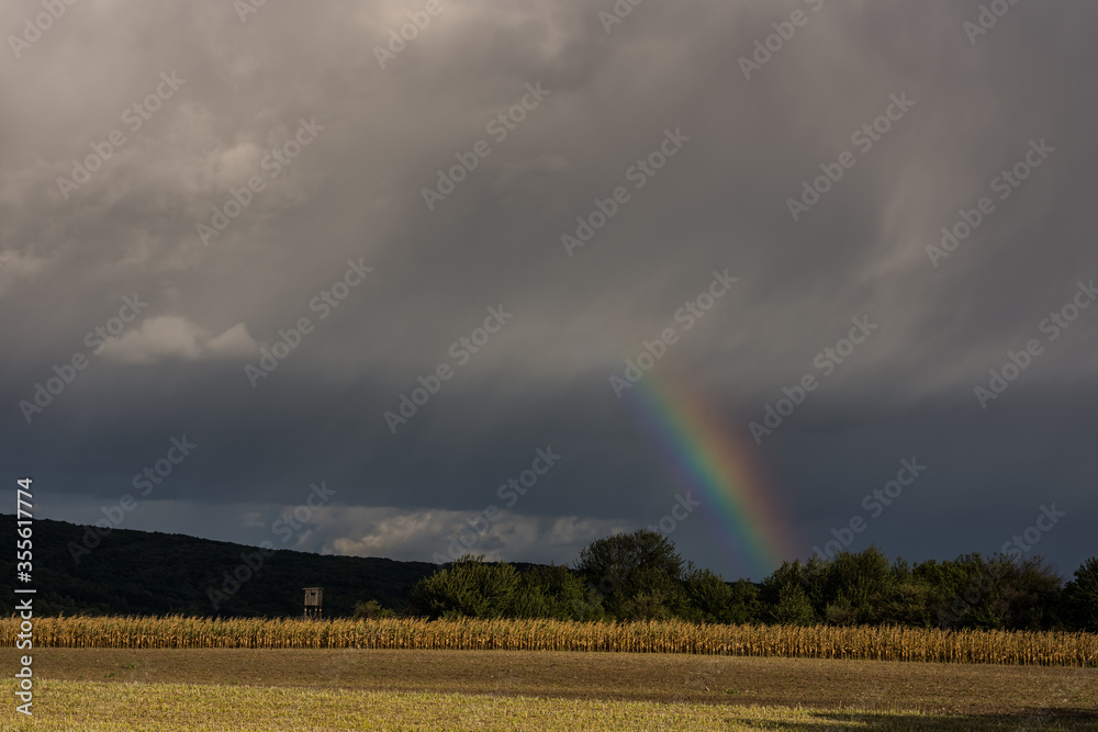 short rainbow with rain clouds during a thunderstorm short rainbow with rain clouds during a thunderstorm
