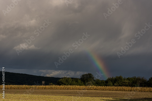 short rainbow with rain clouds during a thunderstorm