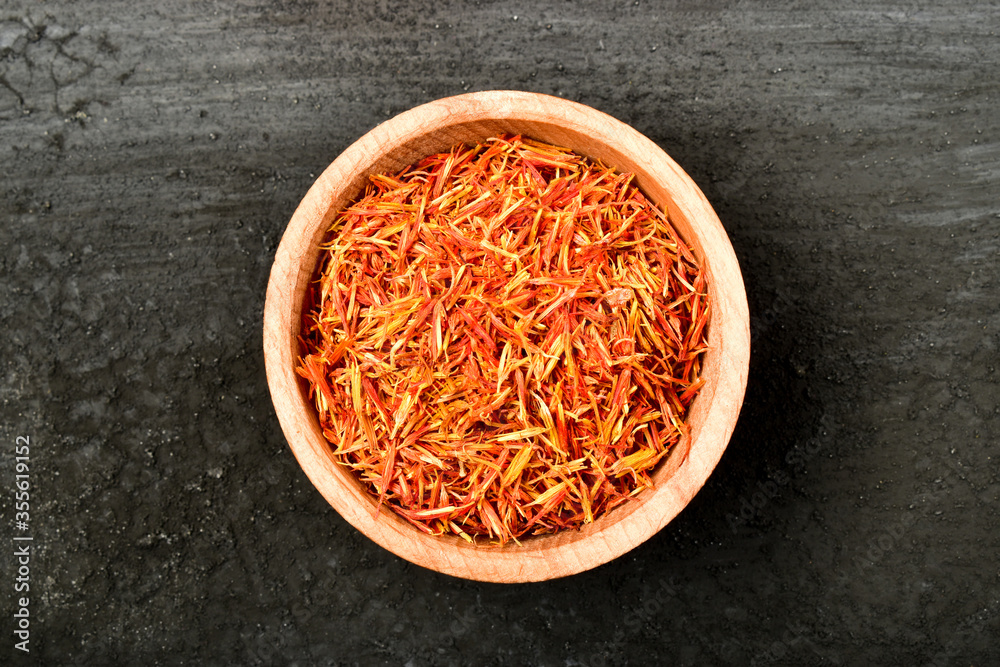 Iranian red saffron spice in wooden bowl isolated on dark colored background Iranian red saffron spice in wooden bowl isolated on dark colored background