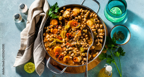banner of Black-eyed Pea Vegan Chili in a metal pan on a wooden stand on a blue background