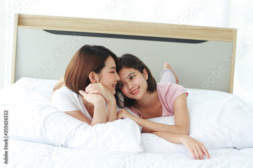 Asian young sisters lovely couple on white bed Smiling together in bedroom. Homosexual women or Lesbian in love. Friendship and Holiday concept.