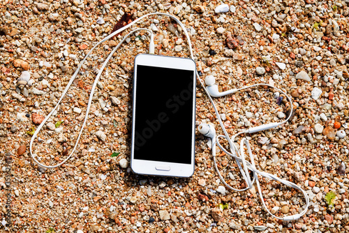 mobile phone with earphone in the sand on the beach