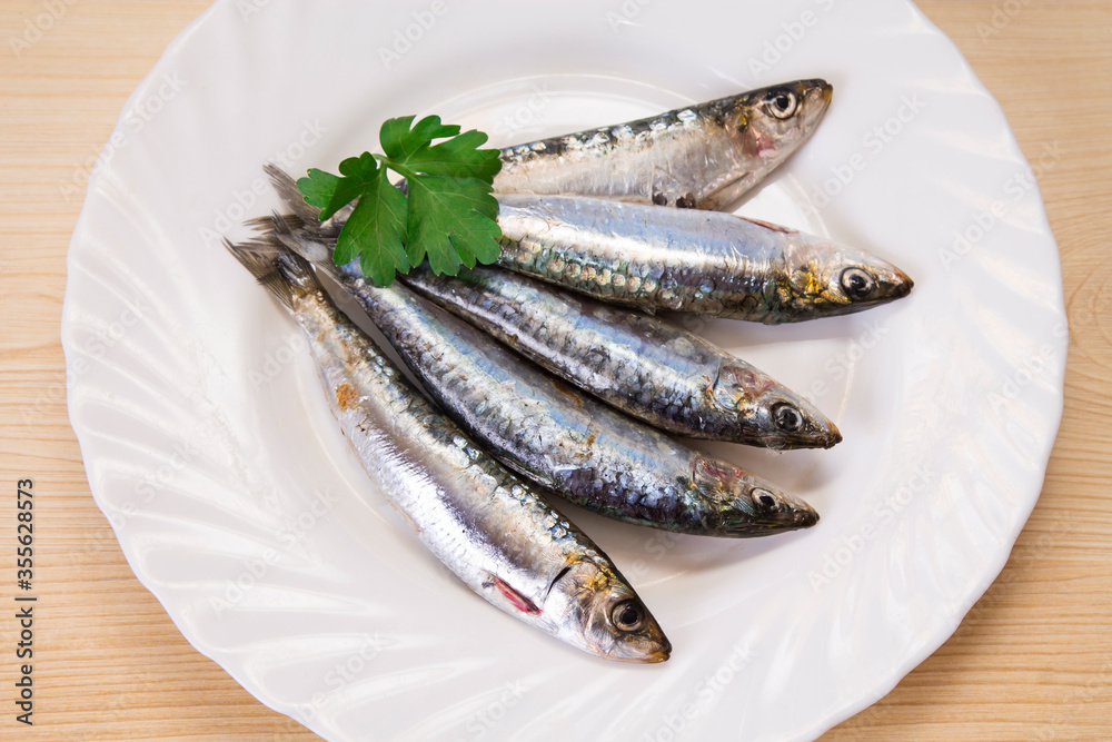 plate of fresh sardines with parsley on the plate plate of fresh sardines with parsley on the plate