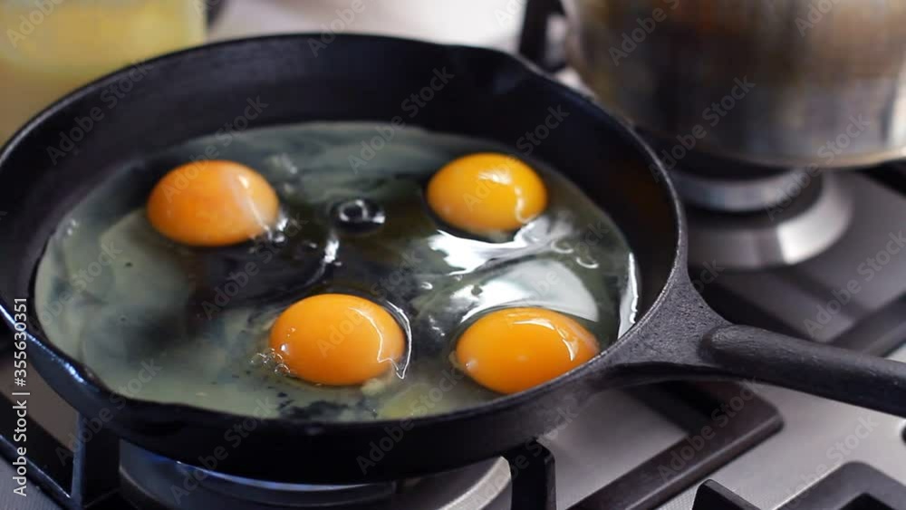 Close-up of cooking fried eggs in black cast-iron frying pan, selective focus Close-up of cooking fried eggs in black cast-iron frying pan, selective focus