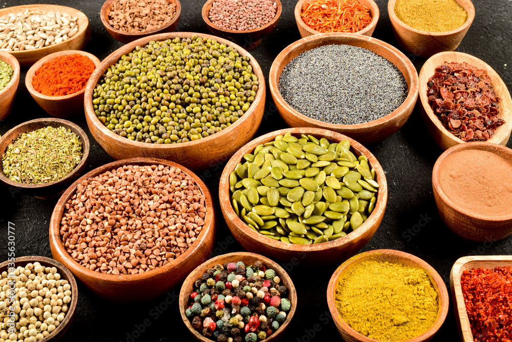 Top view of different kinds of colorful spices in wooden bowls on black stone surface. Top view of different kinds of colorful spices in wooden bowls on black stone surface.