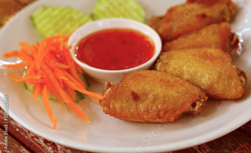 Fried chicken with sauce on a white plate set on a wood table.