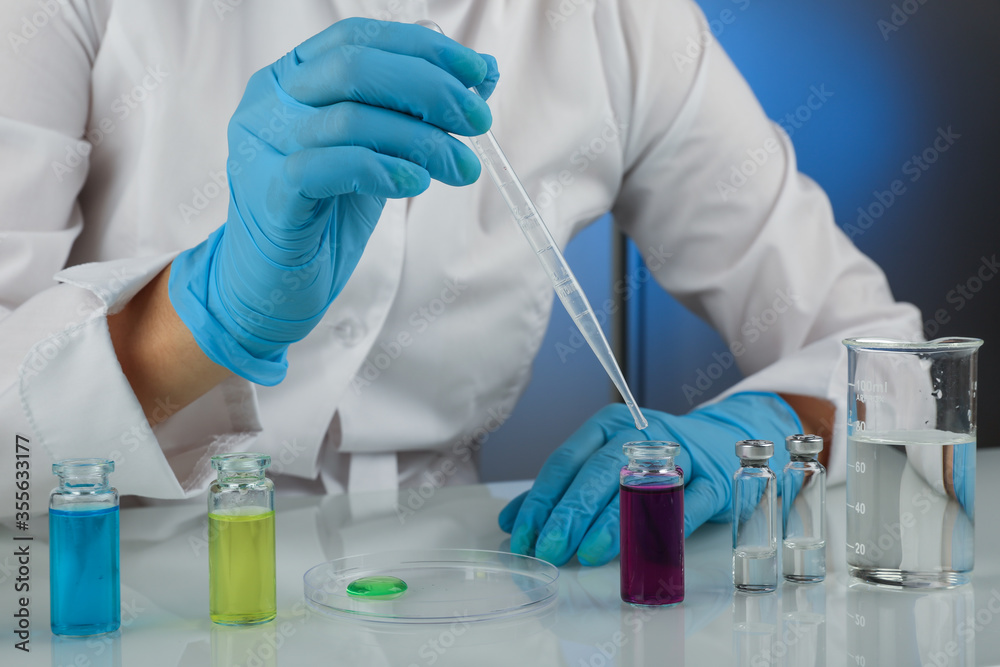 laboratory assistant dropping reagent from a pipette into a test tube laboratory assistant dropping reagent from a pipette into a test tube