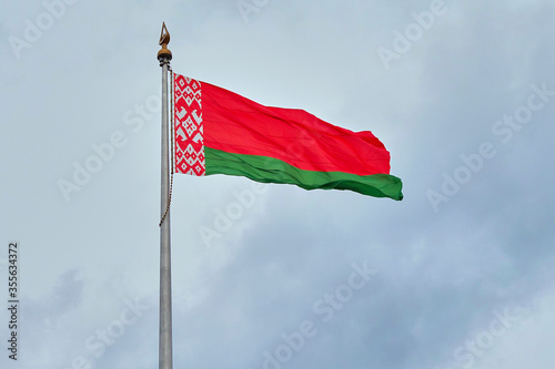 The national flag of the Republic of Belarus on a background of cloudy sky..