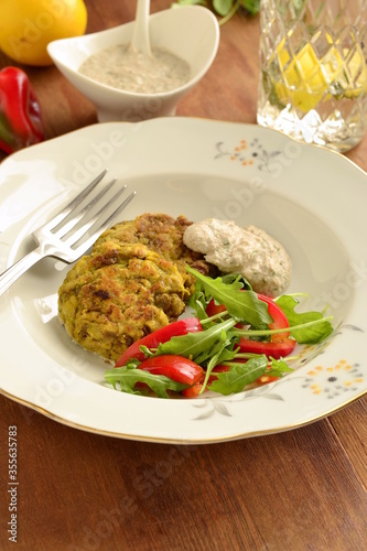 Lentil fritters with zucchini. Served with fresh vegetables and sauce, vertical