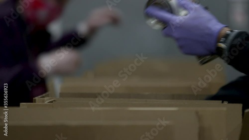 Food bank volunteers out of focus boxing up food donations for people in need during the COVID-19 pandemic