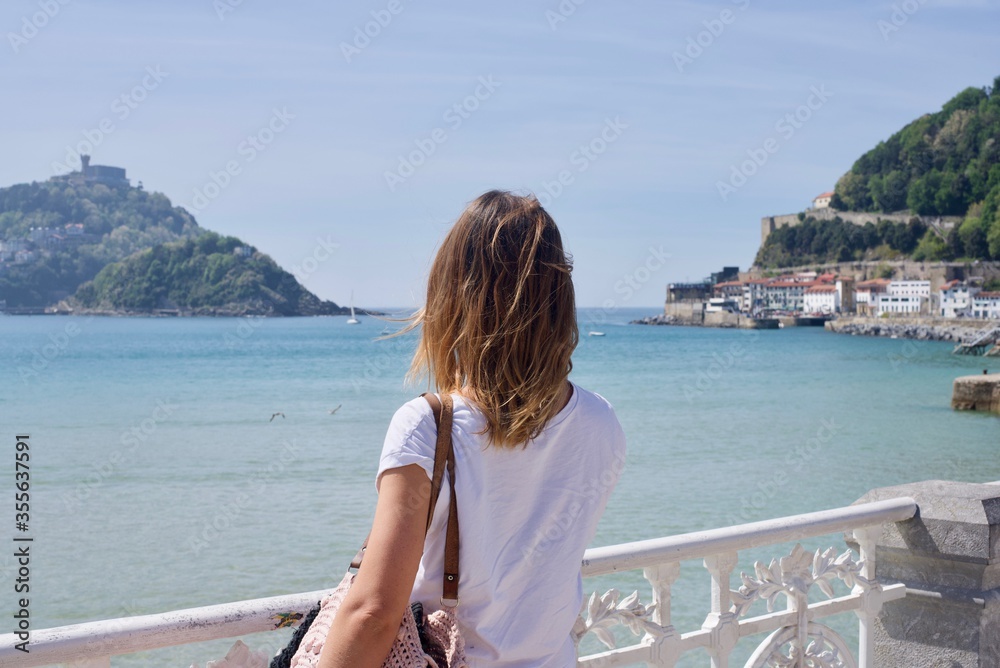 girl looking out to the ocean with a white metal fence
