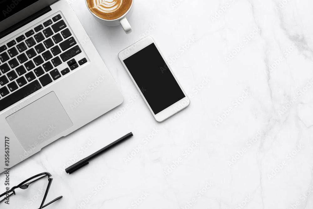 White marble office desk table with laptop computer, smartphone with blank screen, cup of latte coffee and office supplies. Top view with copy space, flat lay. - obrazy, fototapety, plakaty 