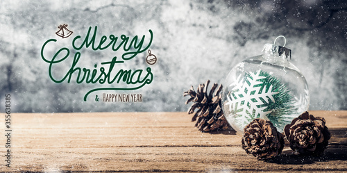 Merry Christmas and happy new year sign with Christmas tree  bauble and pine cone on wood table with concrete wall for celebrate holiday greeting card background