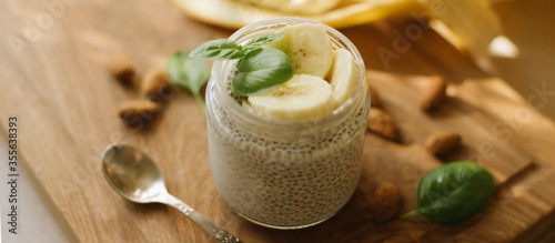 Vegan Chia Pudding with Banana and almond on wooden background. Vegan, morning, breakfast, healthy eating concept. Banner for website
