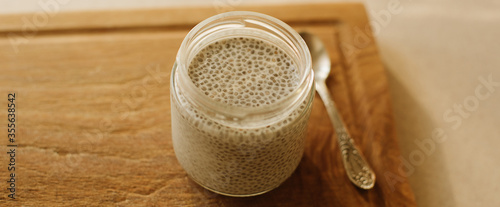Dessert bowl of tasty chia seed pudding on wooden table on white