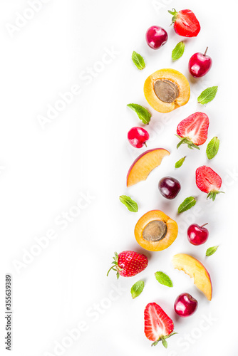 Summer background with fresh fruits and berries on white background. Set of various seasonal fruit and berry - strawberry, apricots, peach slices, cherry, mint. Flat lay. Summer fruits concept.
