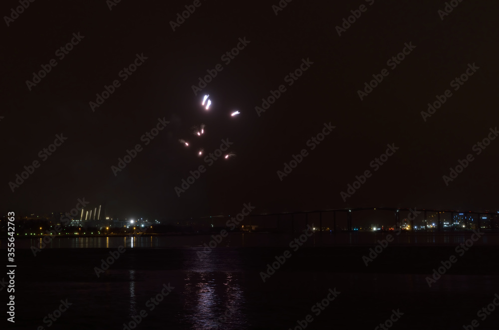 Obraz premium Beautiful firework on night sky in tromsoe city with bridge, cathedral and colorful reflection on the cold fjord water surface on new years eve