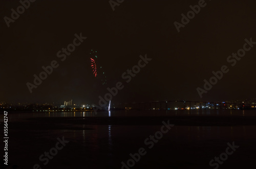 Beautiful firework on night sky in tromsoe city with bridge, cathedral and colorful reflection on the cold fjord water surface on new years eve