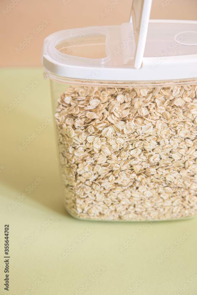 Plastic transparent container with oatmeal on a green background.