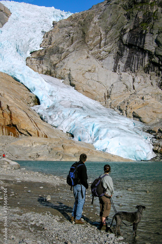 Briksdal Glacier (Briksdalbreen), Norway. Couple with a great dane dog looking at Briskdal Glacier. View of the glacier 10 years ago. photo