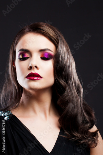 Gorgeous young brunette in a chic evening look. Scarlet lips and eye shadow,