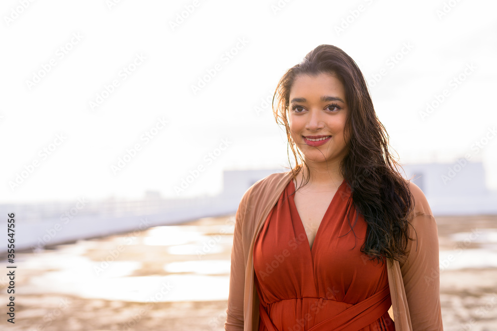Happy young beautiful Indian woman thinking at rooftop of the building Happy young beautiful Indian woman thinking at rooftop of the building