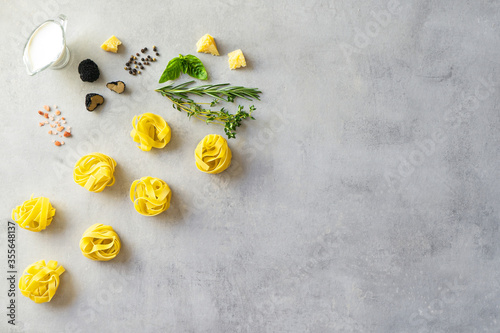 Ingredients for cooking traditional pasta with truffle and sauce ingredients: parmigiano cheese, basil, milk cream, rosemary, thyme, pepper and salt on grey stone background. Top view. Space for text
