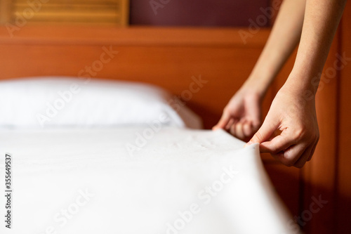 Close up of a woman making the bed. Concept of making the bed. White bed.