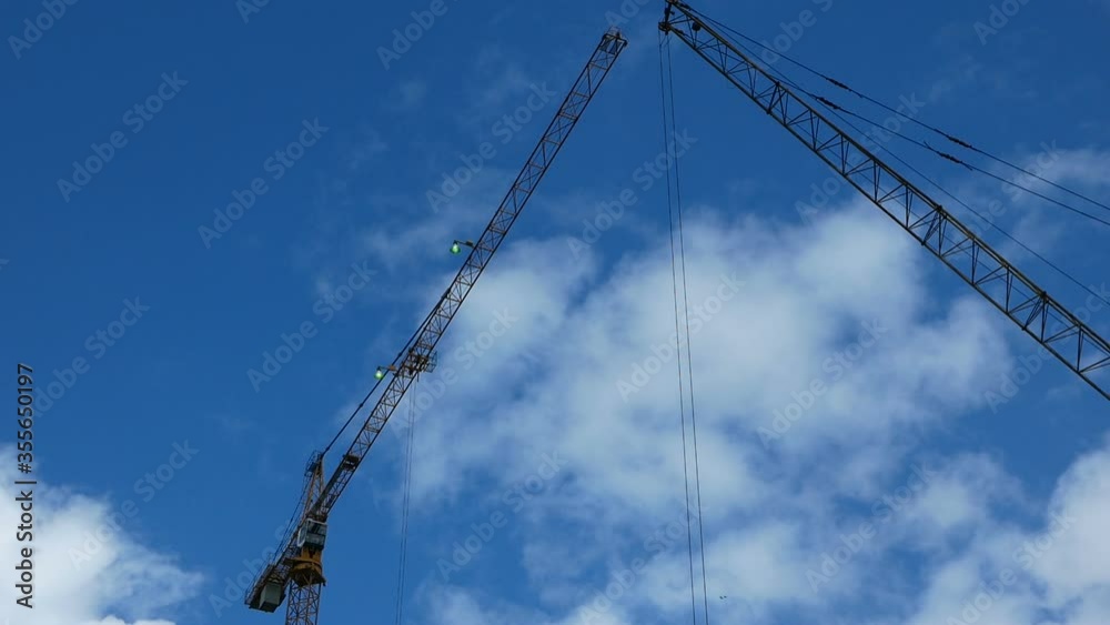 Two working construction cranes on a sunny cloudy day. High-rise building Two working construction cranes on a sunny cloudy day. High-rise building