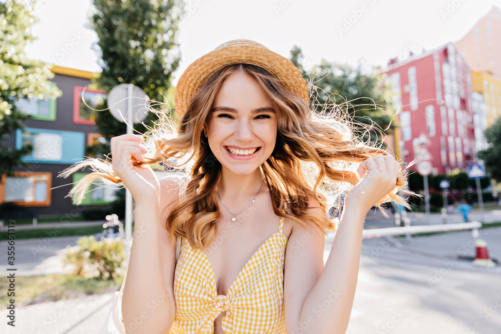 Lovely curly lady in trendy yellow attire enjoying morning. Outdoor photo of blithesome girl having fun in city.
