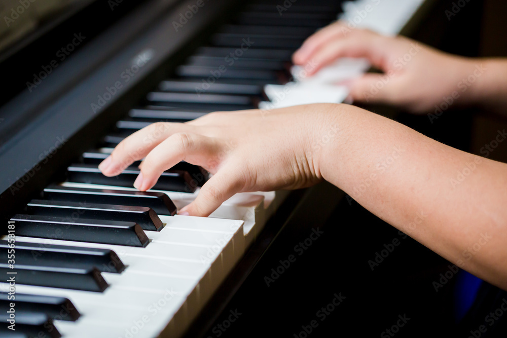 Selective focus to kid fingers and  piano key to play the piano. There are musical instrument for concert or learning music. Close up hand of child musician playing the piano on stage.