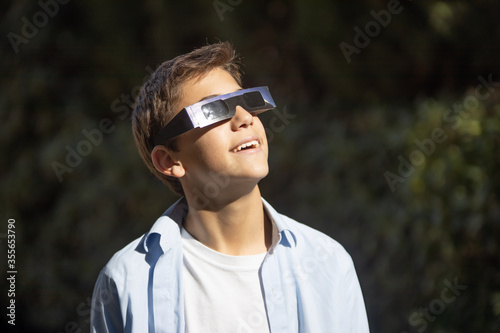 teenager watching an eclipse of the sun with eclipse glasses