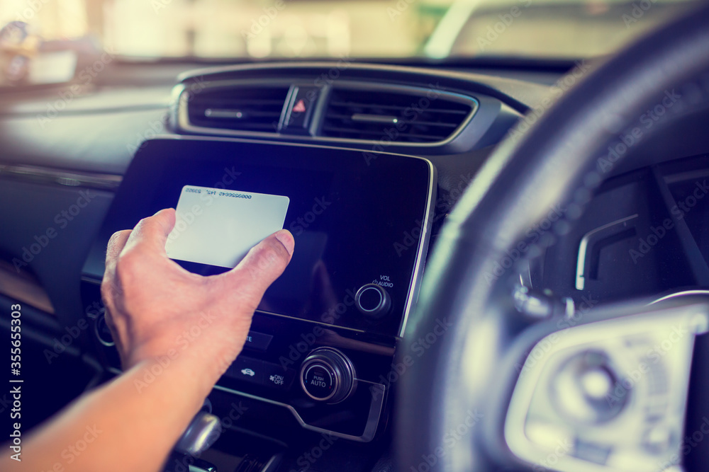 Selective focus to black smart monitor screen at the console with blur driver's hand holds a smart card to read information in the car. Selective focus to black smart monitor screen at the console with blur driver's hand holds a smart card to read information in the car.