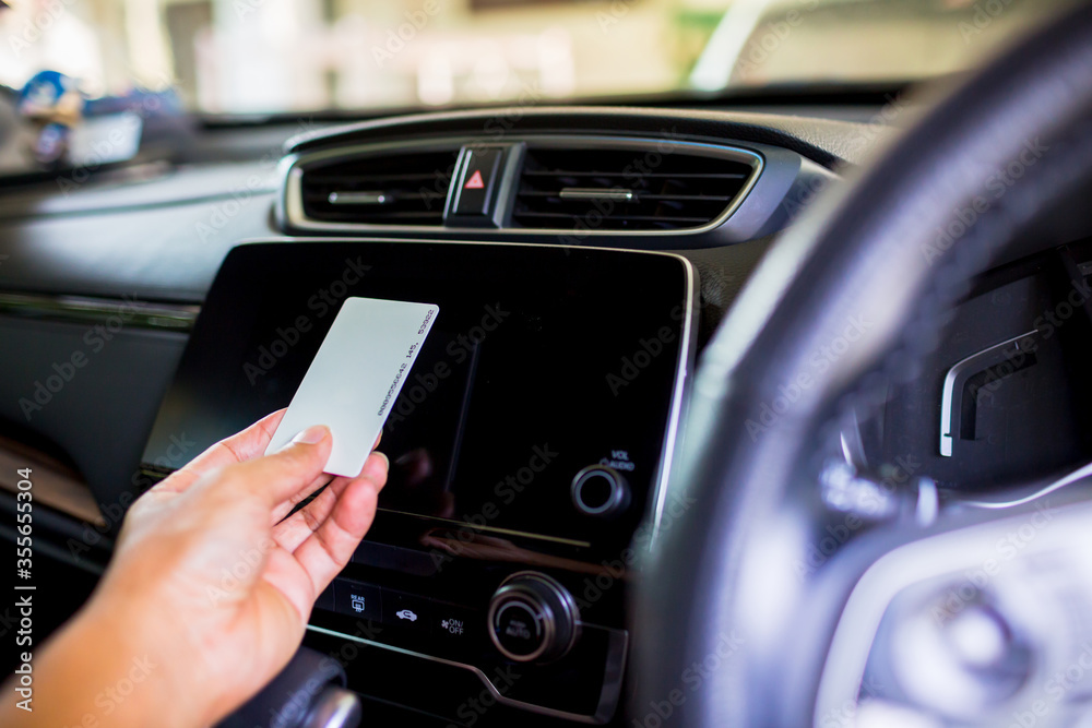 Naklejka premium Selective focus to the driver's hand holds a smart card to read the information on the smart monitor screen at the console in the car. The concept of smart car.