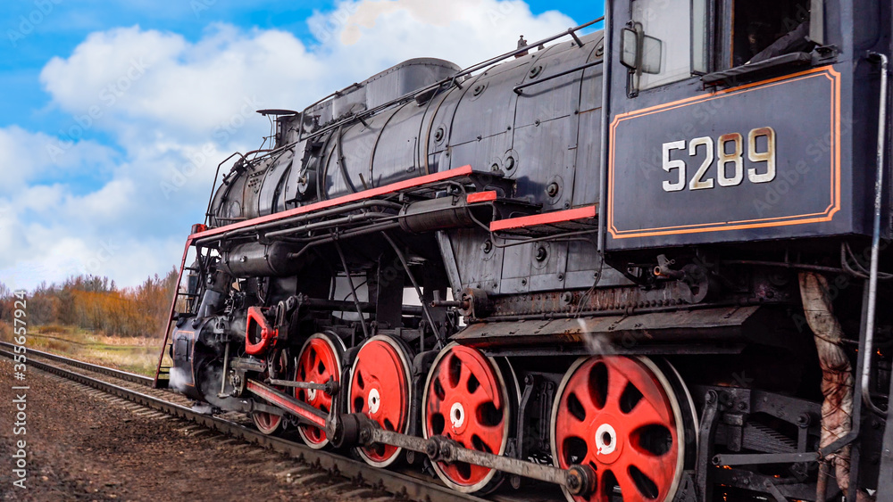 Obraz premium Retro steam train rides by rail on the blue sky background. Railway worker's day
