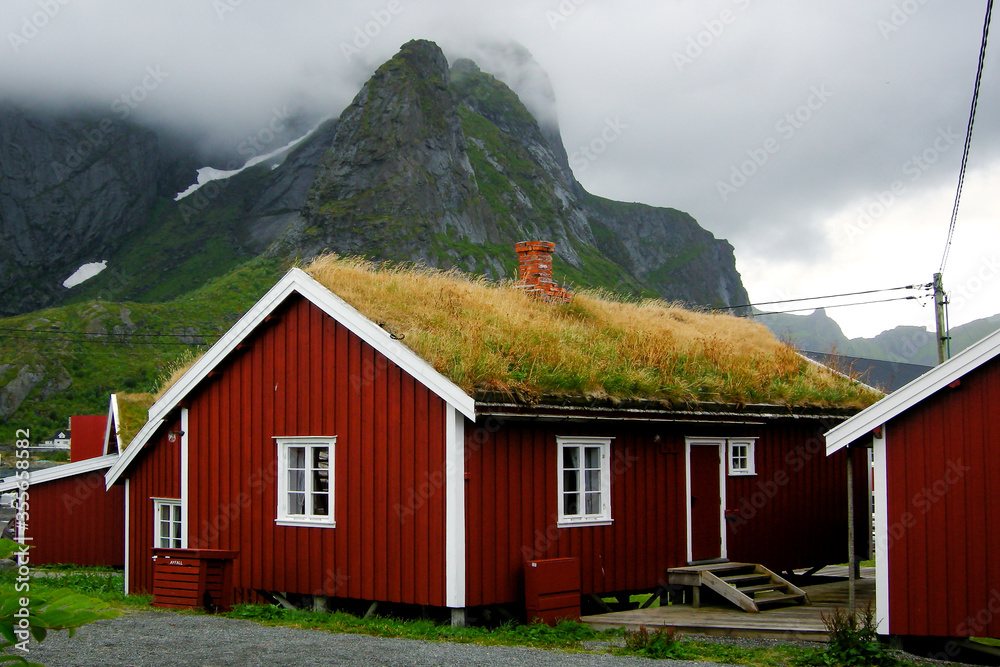 Reine, Lofoten Islands, Norway. House with traditional grass roof in Reine, with mountain in mist in the background.