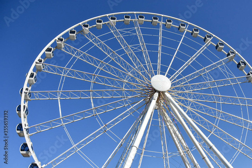 The Great Smoky Mountain wheel at The Island in Pigeon Forge, Tennessee, USA.  The giant wheel is set against a plain bright blue cloudless sky background photo