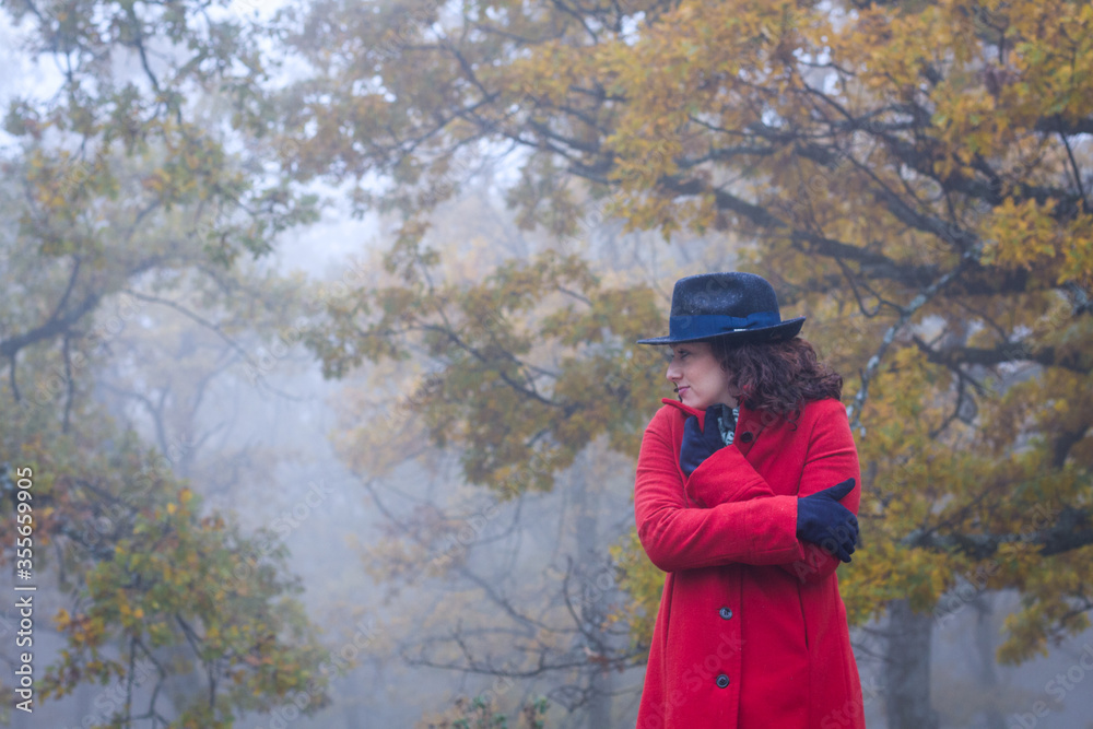 Horizontal view of misterious woman surrounded by scary autumn oak forest in the fog waiting for someone. Horizontal view of misterious woman surrounded by scary autumn oak forest in the fog waiting for someone.