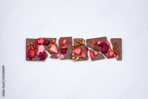 A broken chocolate bar with nuts and dried berries.