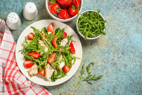 Green salad with chicken, strawberry and arugula.