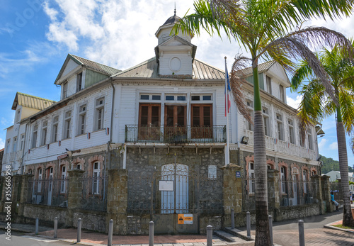 Le Francois, Martinique - September 18, 2018: Hotel de Ville, City Hall - old building with a flag and palm trees. Blue sky. White clouds. Copy space photo