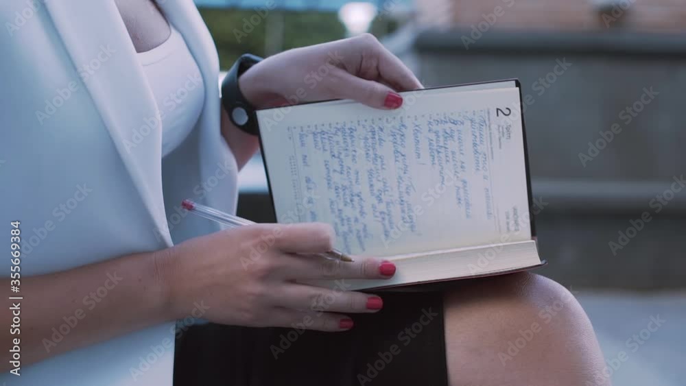 Close-up of young entrepreneur writing notes in diary during work break