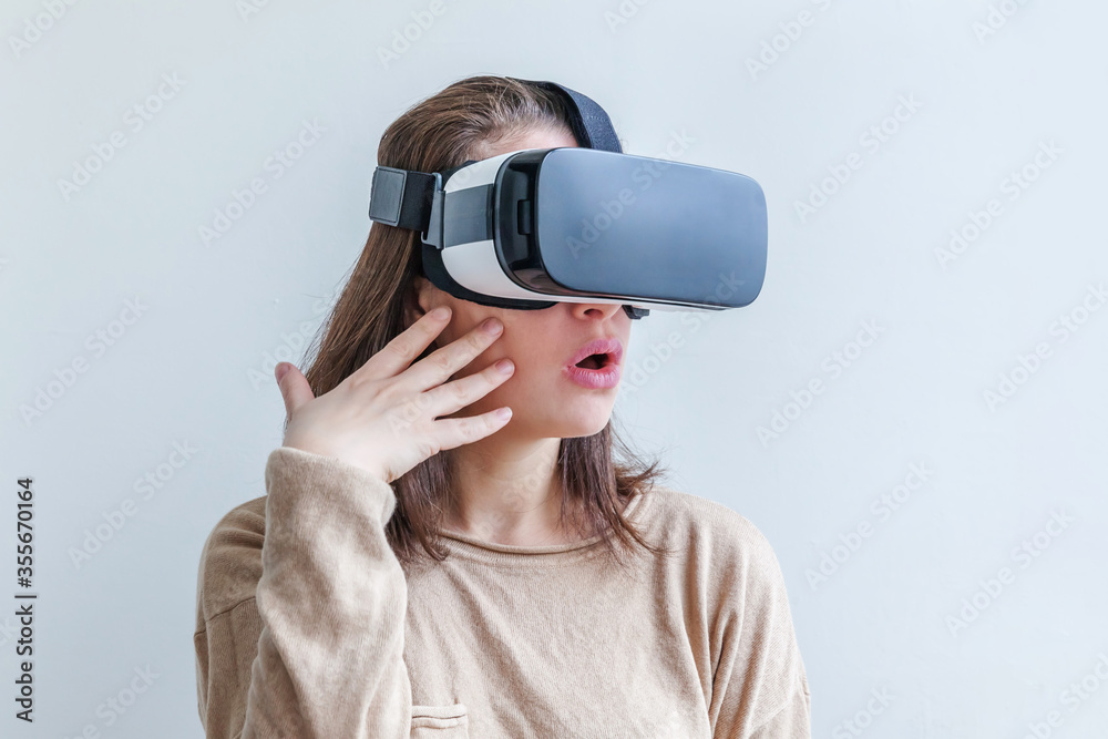 Smile young woman wearing using virtual reality VR glasses helmet headset on white background. Smartphone using with virtual reality goggles. Technology, simulation, hi-tech, videogame concept Smile young woman wearing using virtual reality VR glasses helmet headset on white background. Smartphone using with virtual reality goggles. Technology, simulation, hi-tech, videogame concept