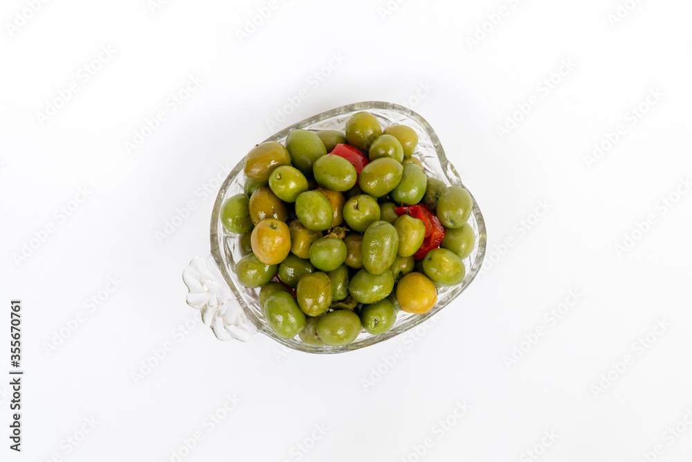 Marinated olives in small transparent bowl. On white background. Pickled green olives