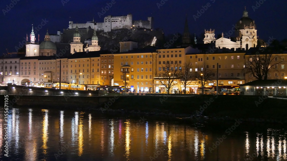 Nachtaufnahme vom historischen Salzburg mit Blick zur Festung Hohensalzburg und der Salzach im Vordergrund
